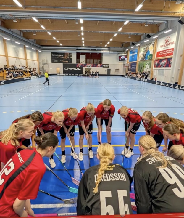 Innebandylag står i grupp inomhus i sport hall